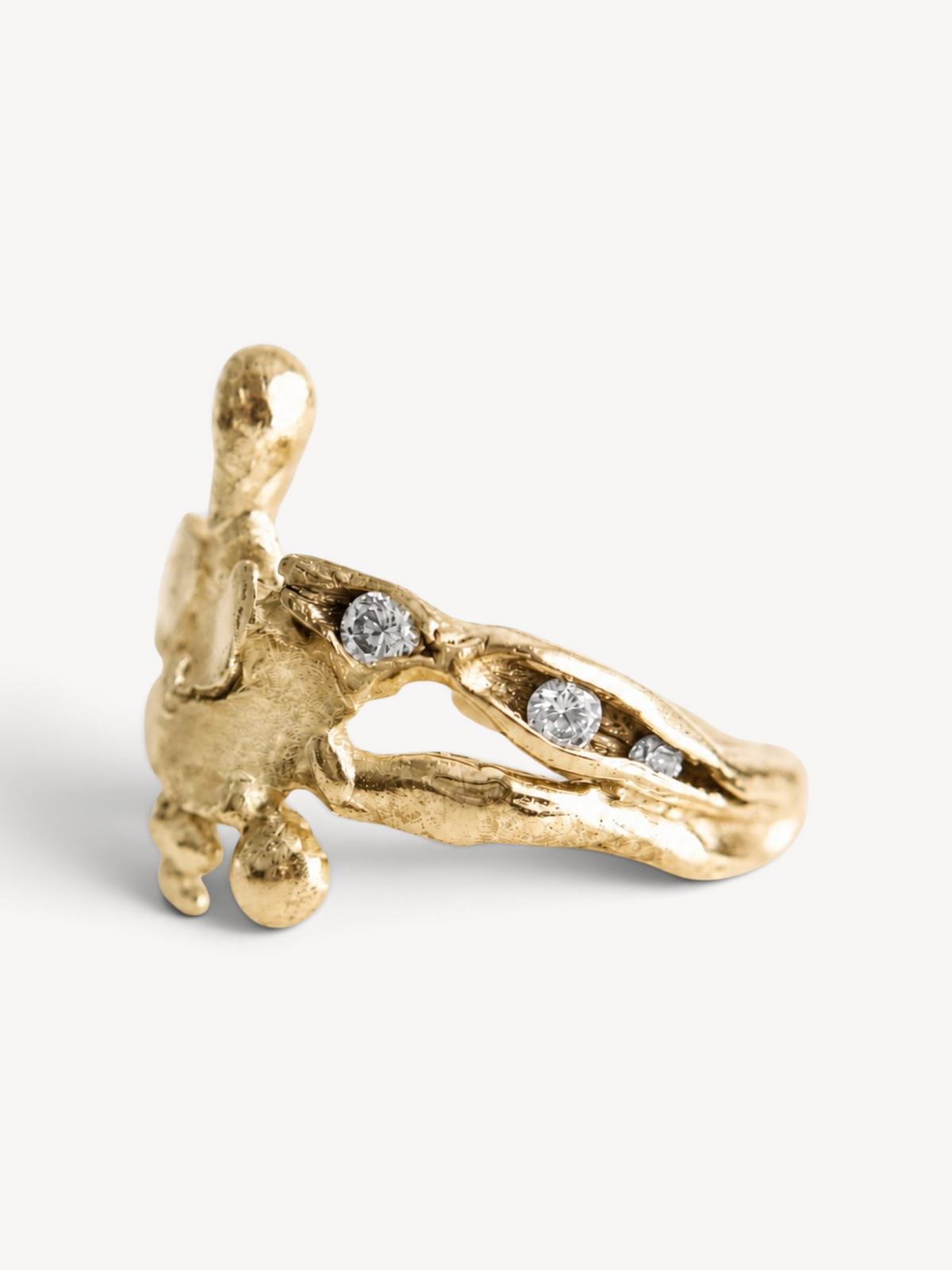 Angled side profile of a sculptural 14k gold plated sterling silver ring featuring six white zircon stones.