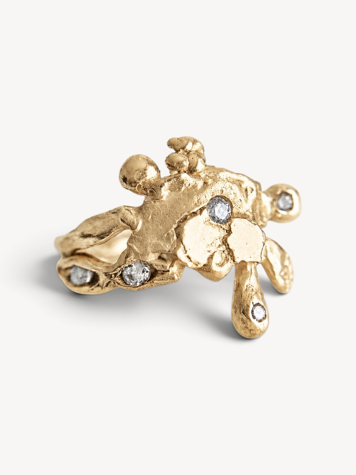 Overhead view of a contemporary 14k gold plated sterling silver ring highlighting its organic sculptural details and six white zircon stones.