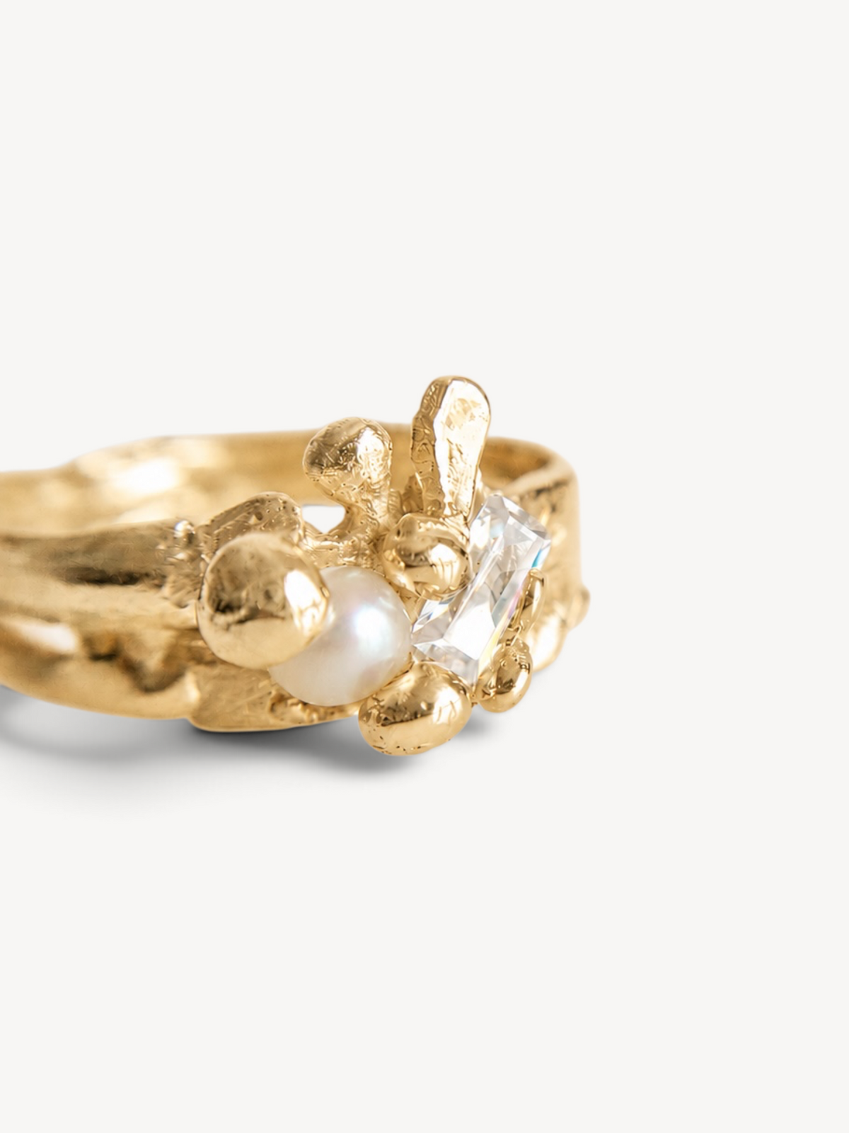Close-up of a handcrafted 14k gold-plated sterling silver ring featuring a freshwater pearl, rectangular-cut white zircon, and an organic sculptural design.