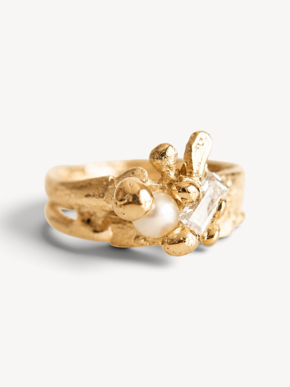 Three-quarter close-up of a handcrafted 14k gold-plated sterling silver ring showcasing a freshwater pearl and rectangular-cut white zircon.