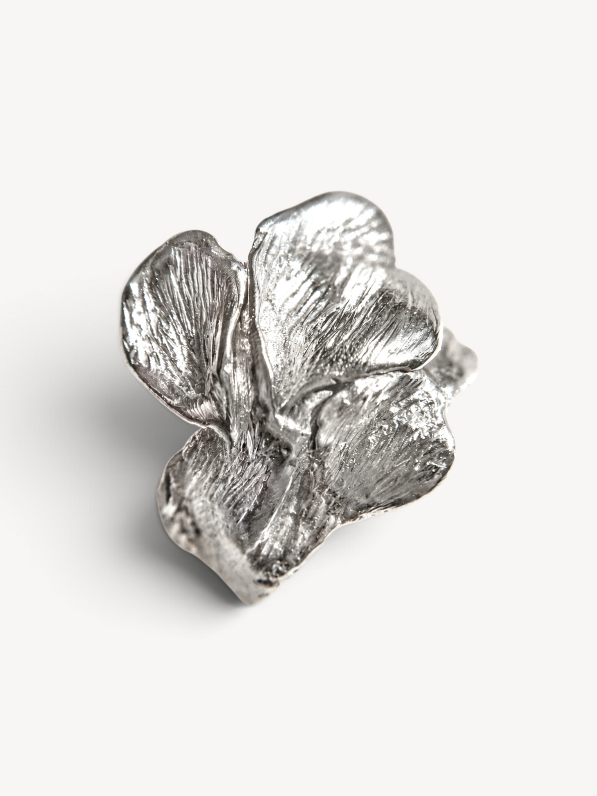 Angled front view of a handcrafted rhodium-plated sterling silver sculptural ring with an organic leaf-inspired design.