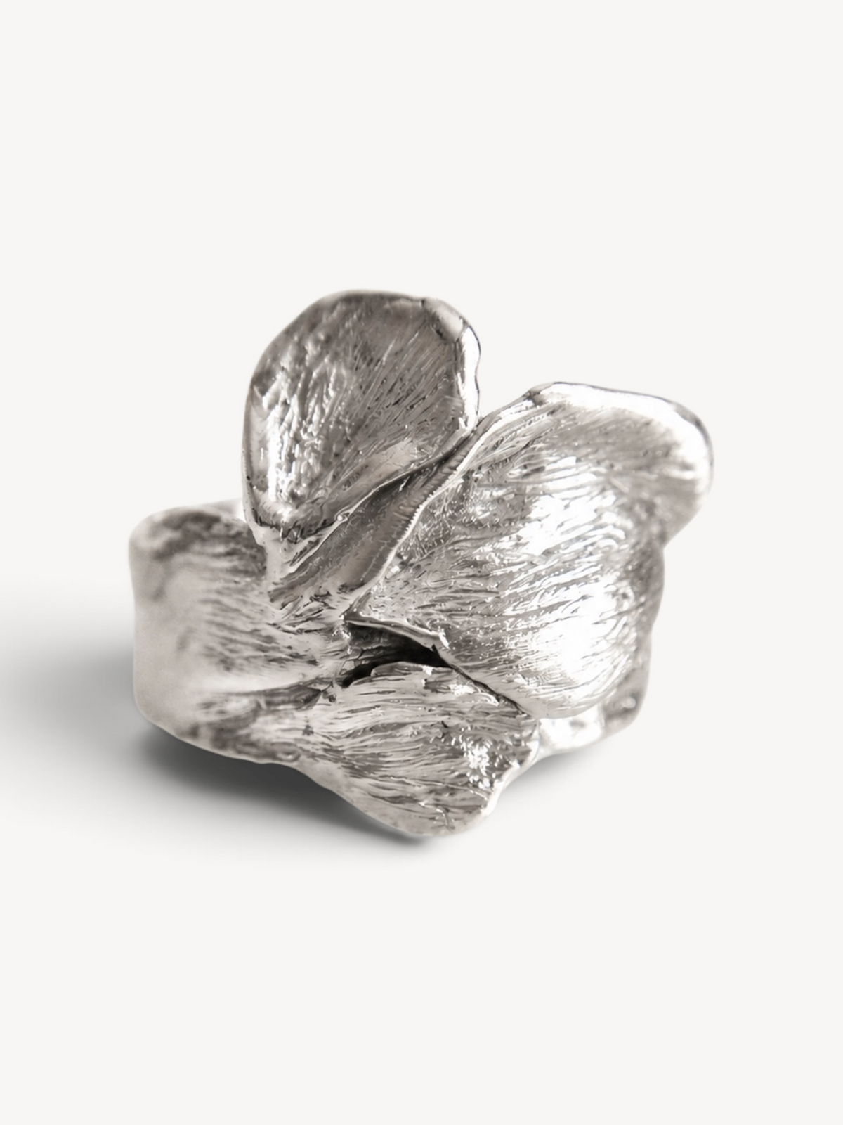 Front view of a contemporary rhodium-plated sterling silver statement ring featuring layered organic leaf textures.